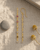 Dainty multi-color tourmaline dangle earrings displayed on a linen journal flatlay