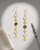 Brass dangle earrings featuring labradorite and moonstone gemstones photographed under spotlight lighting on neutral background