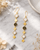 Brass drop earrings featuring labradorite and moonstone gemstones displayed on white marble surface
