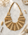 Beige statement bib necklace with layered tonal beads displayed on white marble surface