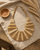 Beige statement bib necklace with layered tones displayed on linen fabric beside a journal