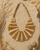 Beige statement bib necklace with layered tones displayed on sandy pebble outdoor surface