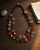 Double-Strand Deep Red and Gray Horn Necklace with Brass Accents — necklaces, editorial wood console lifestyle photo