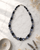 Hand-Painted Black Ceramic Pottery Bead Necklace with Metal Accents — necklaces, editorial marble lifestyle photo