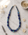 Hand-Painted Floral Ceramic Bead Necklace with Crochet Accents — necklaces, editorial marble lifestyle photo