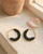 Black beaded crescent hoop earrings resting on a sunlit outdoor window ledge
