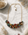 Kantha beaded cluster necklace styled as a convertible choker on a white marble surface