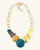 Side-angle flat lay of patina brass disc cascade necklace displaying chain length and profile of individual disc pendants