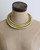 Hand-beaten brass triple-strand collar necklace on a tan dress form mannequin, angled front view showing fit