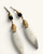 Close-up detail of both Kenyan artisan earrings showing brass coil caps, black beads, spiral motif, and carved bone pendants