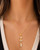 Triple Herkimer Quartz gold-plated pendant worn on a gold chain around a model's neck over a white top, worn view