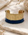 Hand-hammered brass cuff bracelet with indigo painted lower band and scalloped edges, front view on stone surface with dried botanicals