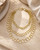 Brass three-strand circular link chain necklace flat lay on stone surface with toggle clasp visible, warm styled shot