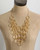 Hand-hammered brass ring bib necklace on a tan fabric dress form showing full bib spread and gold cable chain