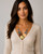 Hammered Brass & Copper Tri-Tone Disc Necklace worn by a model in a cream ribbed cardigan, front view showing disc arrangement and length