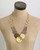 Hammered Brass & Copper Tri-Tone Disc Necklace displayed on a tan dress form, front view showing graduated disc layout and ring chain