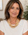 Five-strand bone bead layered necklace worn by a woman in a white top, close-up portrait showing drape at neckline