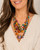 Kantha four-strand statement necklace worn by a model in a cream v-neck top, showing layered multicolor fabric beads