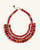 Red textile-wrapped bead layered bib necklace flat lay, four rows of mixed red beads with gold wire connectors and clasp