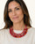 Red textile-wrapped bead layered bib necklace worn by a model in a cream top, close-up showing three rows at the neckline