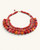 Red textile-wrapped bead layered bib necklace at an angle on white background, showing four-row bib depth and gold wire links