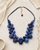 Kantha recycled sari textile bead layered necklace in indigo blue laid flat on a linen surface with dried botanicals