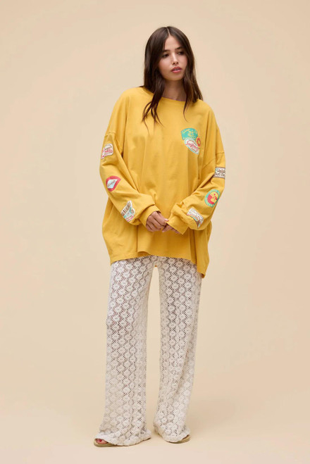 woman in a long-sleeve yellow shirt with patch style work on the sleeve