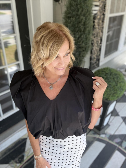 Woman posing in a flowy black v-neck blouse
