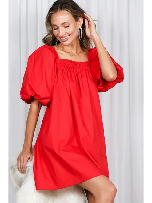 Woman posing in a scarlet red puff sleeved mini dress with rounded neckline
