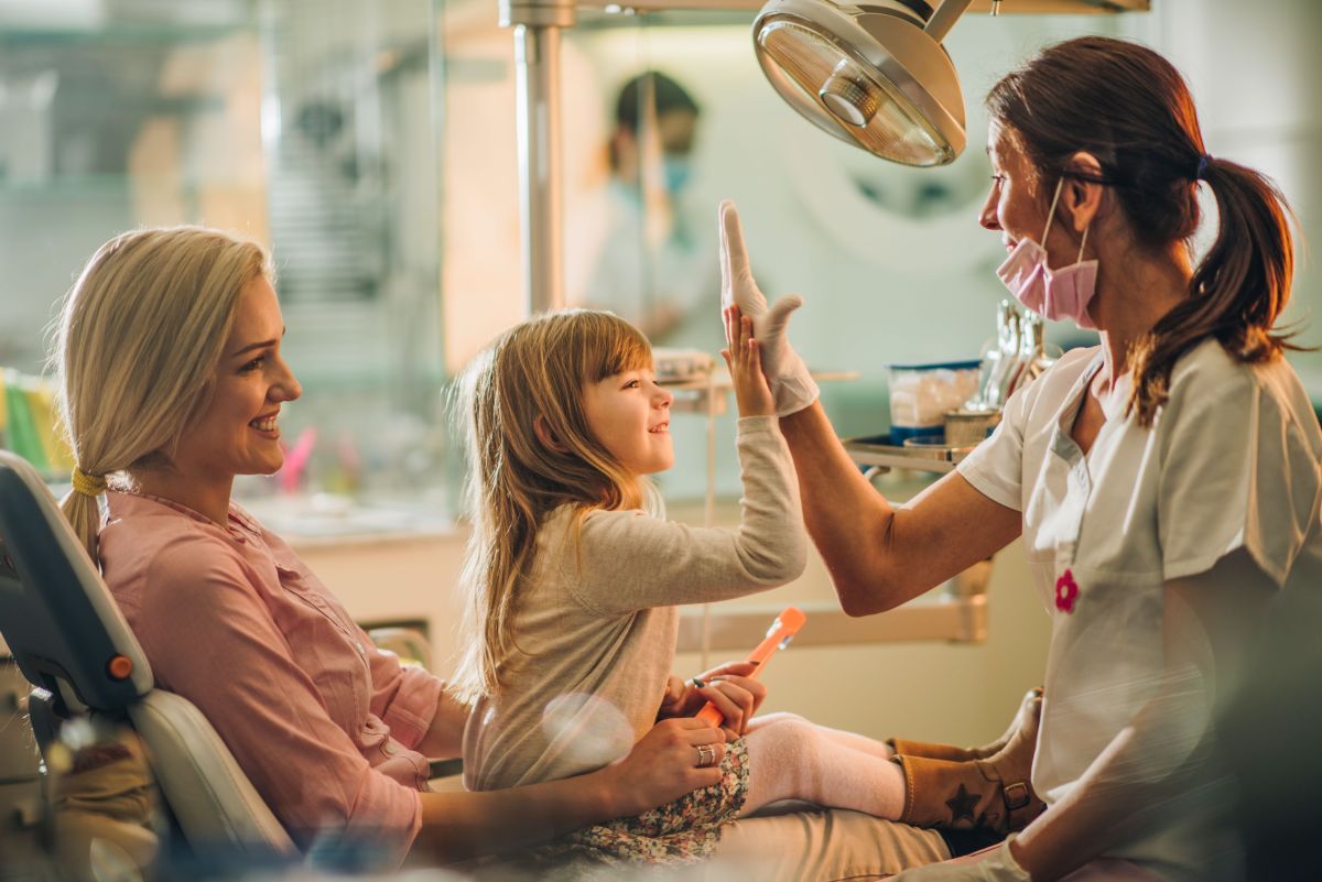 A Dental Professional with a young girl and her mother at the clinic