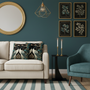 Warm living room detail with teal and gold crane decorative pillows on cream sofa, natural morning sunlight and plants
