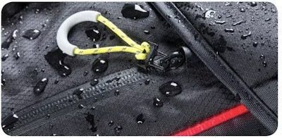 Close-up of a waterproof bag with water droplets on the surface, featuring a yellow and white carabiner attached to a zipper pull.
