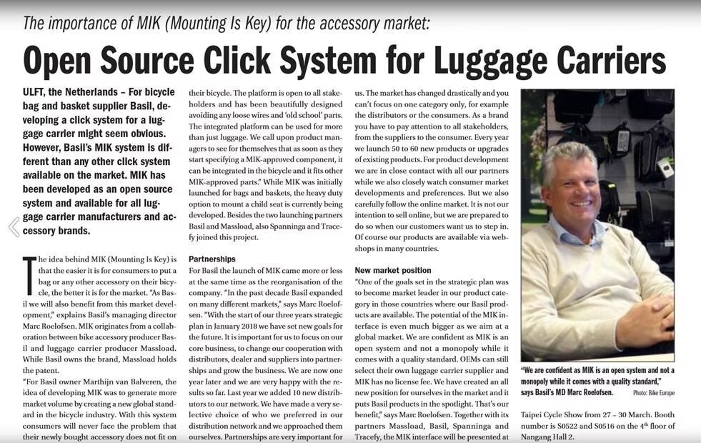 Article discussing the importance of MIK open source click system for luggage carriers, featuring a photo of a smiling man seated next to bicycle accessories.