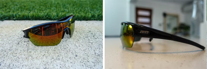 Two images of black sports sunglasses with reflective yellow-orange lenses; one outdoors on concrete with grass, the other indoors on a countertop.