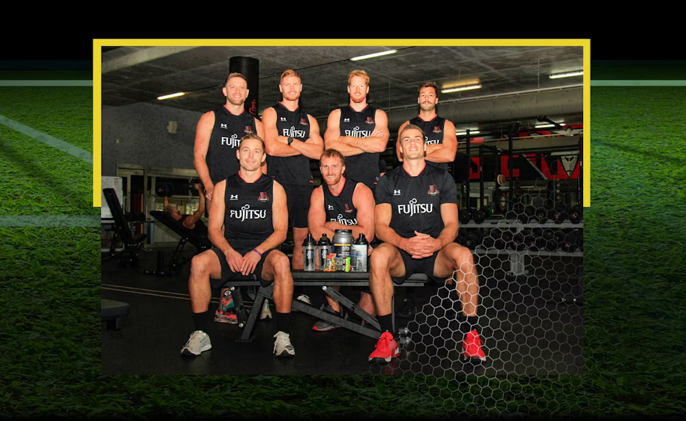 Group of athletes wearing Fujitsu-branded gym attire posing in a gym setting.