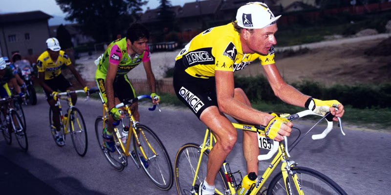 Cyclists competing in a race, wearing yellow jerseys and riding on a road.
