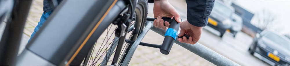 Person securing a bicycle to a metal railing using a sturdy U-lock.