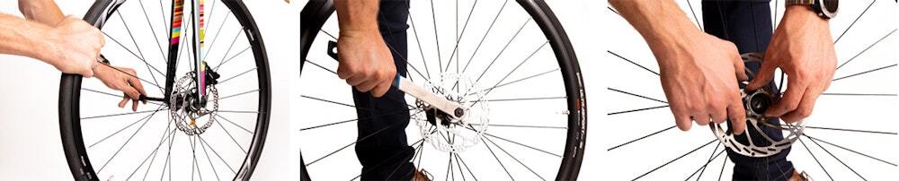 Hands unscrewing and working on a bicycle wheel hub with a rotor
