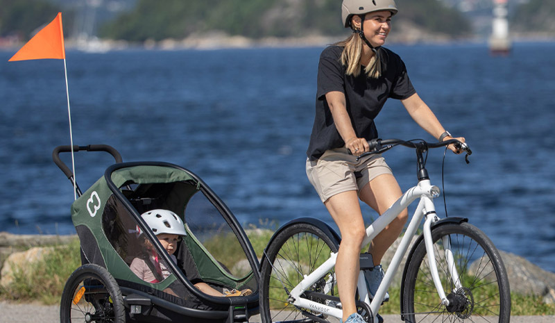 parents cycling with child in Hamax Outback trailer spring weather