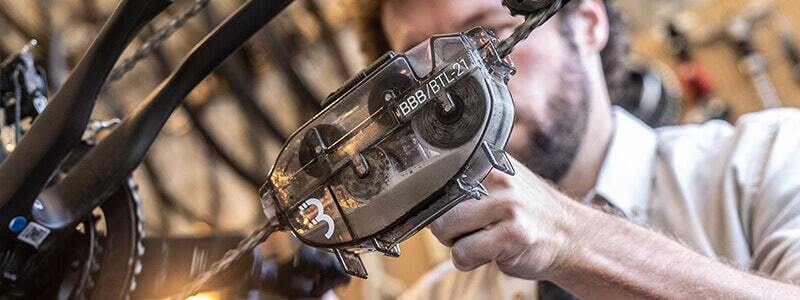 Person using a Bright & Fresh chain cleaner tool on a bicycle chain.