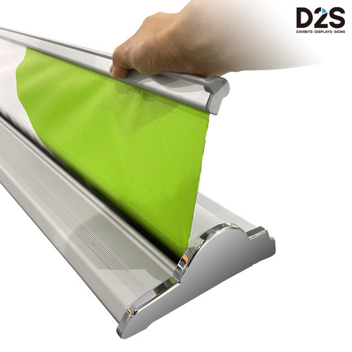 Close-up of banner graphic insertion into D2S retractable banner stand base with adhesive connector system and green vinyl panel