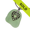 A large piece of natural vivid seafoam green sea glass set on a solid sterling hand cast bail with a sterling silver heart in hearts charm. A perfect sea glass necklace for any sea glass lover!