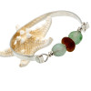 A thick bright amber sea glass center bead and two recycled green glass beads set with sterling details on a solid sterling flat bangle bracelet.
