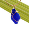 A nice irregular shaped piece of genuine blue sea glass in a gold deco inspired necklace setting.