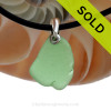 A smaller piece of  Green Natural Sea Glass Necklace Set On Silver Bail With Black Neoprene Cord with sterling clasps.