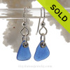 A pair of natural surf tumble sea glass earrings in a lucky cobalt blue on sterling fish hooks.