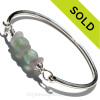 3 Pale Lavender or Purple sea glass pieces set with a recycled seafoam green glass beads set with sterling details on a solid sterling full found bangle bracelet.