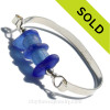 A collection of blue beach found glass beads set with sterling details on a thick Solid Sterling flat bangle bracelet.