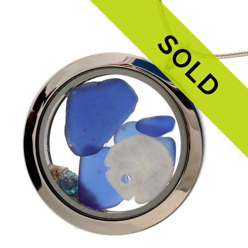 A beautiful and rare pieces of blue sea glass combined with a real sandollar, zircon or aqua colored gems (great for a december birthday)  in this one of a kind sea glass locket necklace.
Real beach sand from Florida completes your own personal beach on the go!