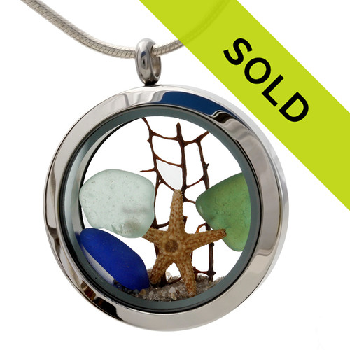 Blue , seafoam green and olive green sea glass pieces combined with a real starfish, a piece of seafan and beach sand in this sea glass locket necklace.